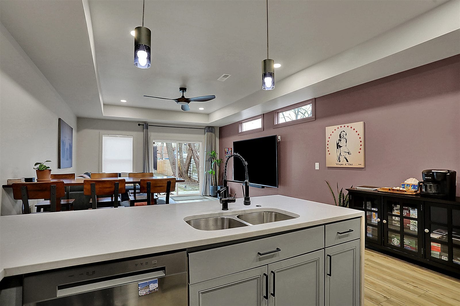 Open main-floor living room with sectional, wall TV, dining bar, and slider to fenced yard