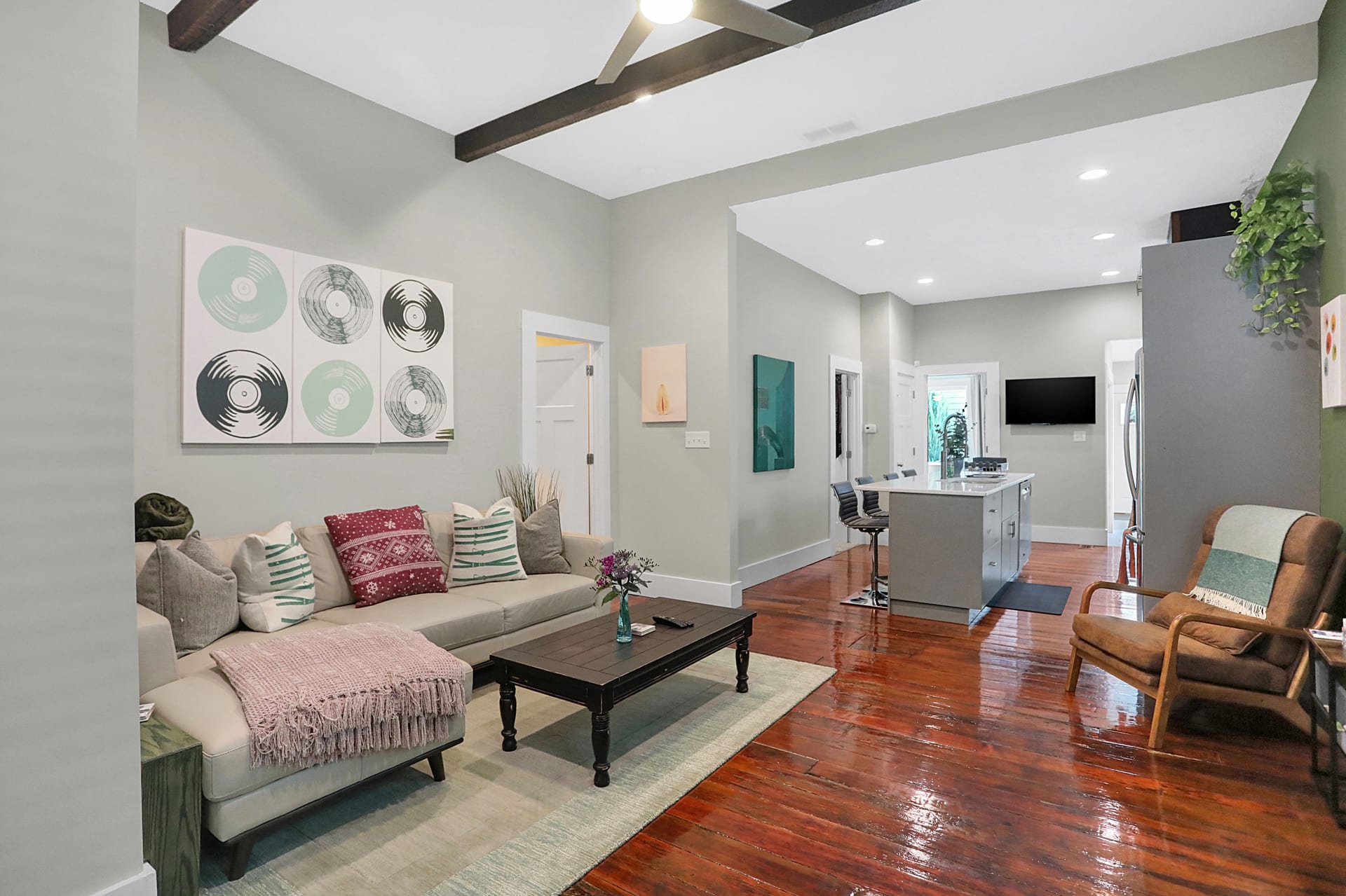 Open living room with exposed barn beams, original hardwood floors, and sightline through to the kitchen