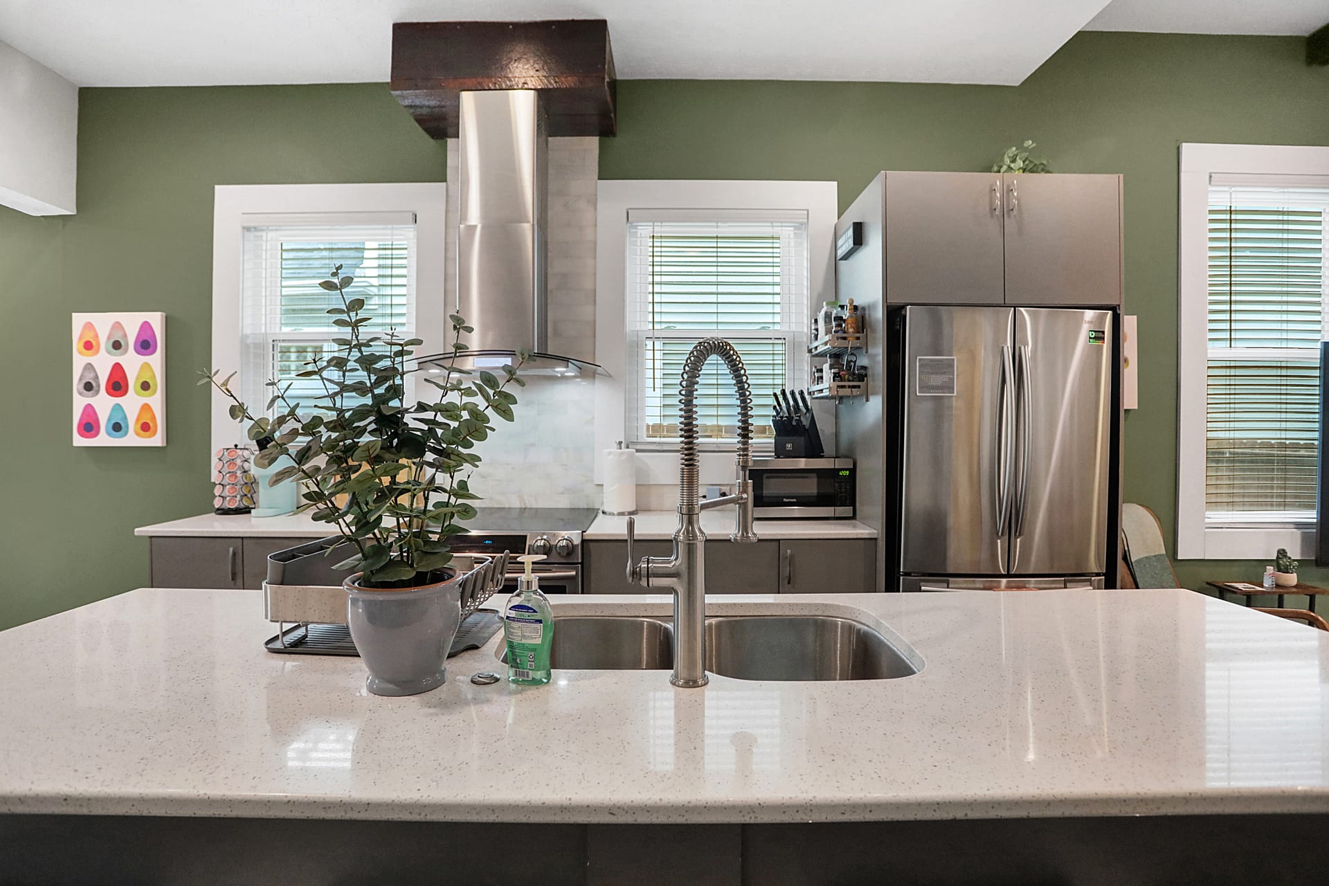 Close view of the kitchen island, farmhouse sink, and stainless French-door refrigerator at The Sanders