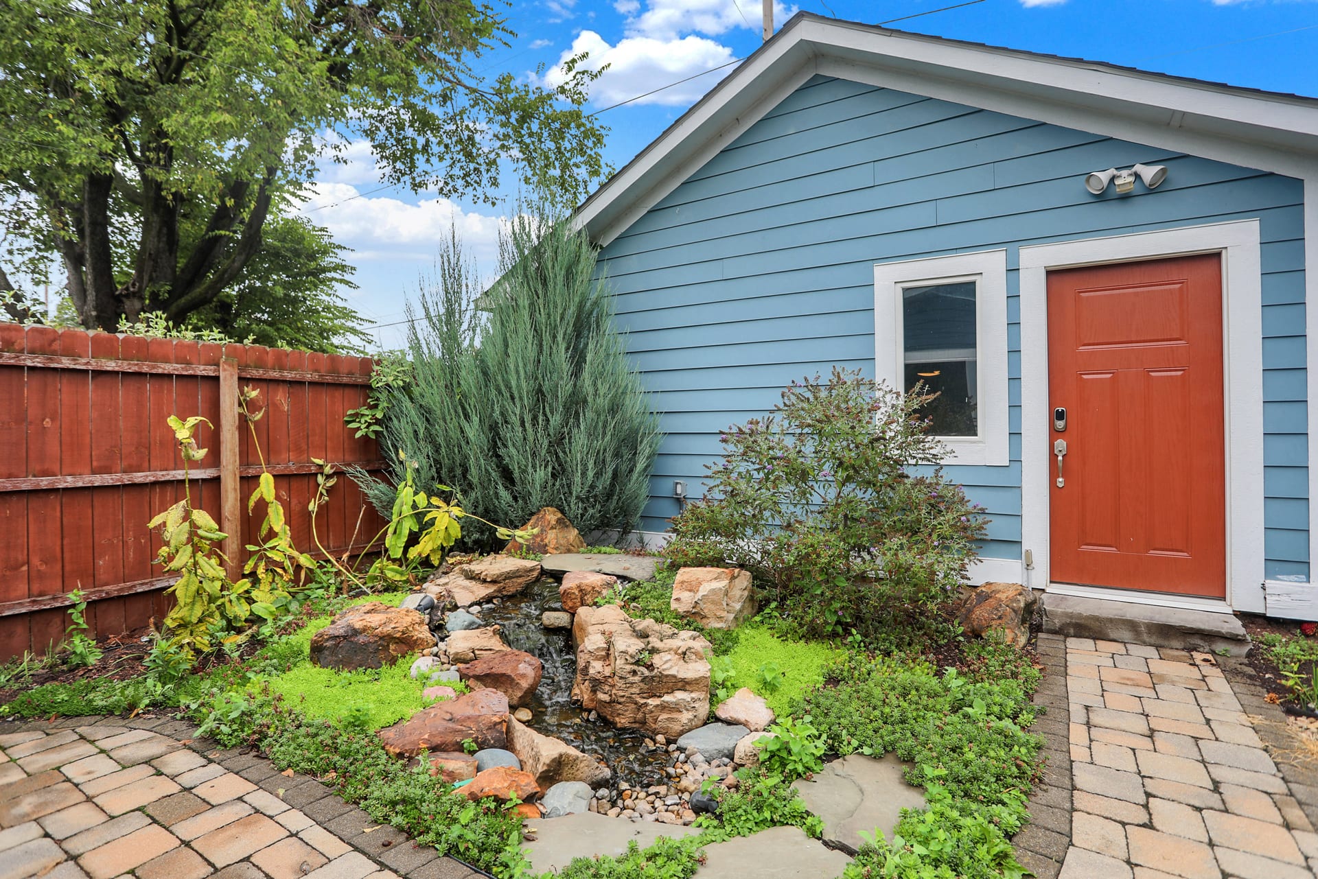 Detached garage entry door and stone water feature garden at the rear of The Sanders