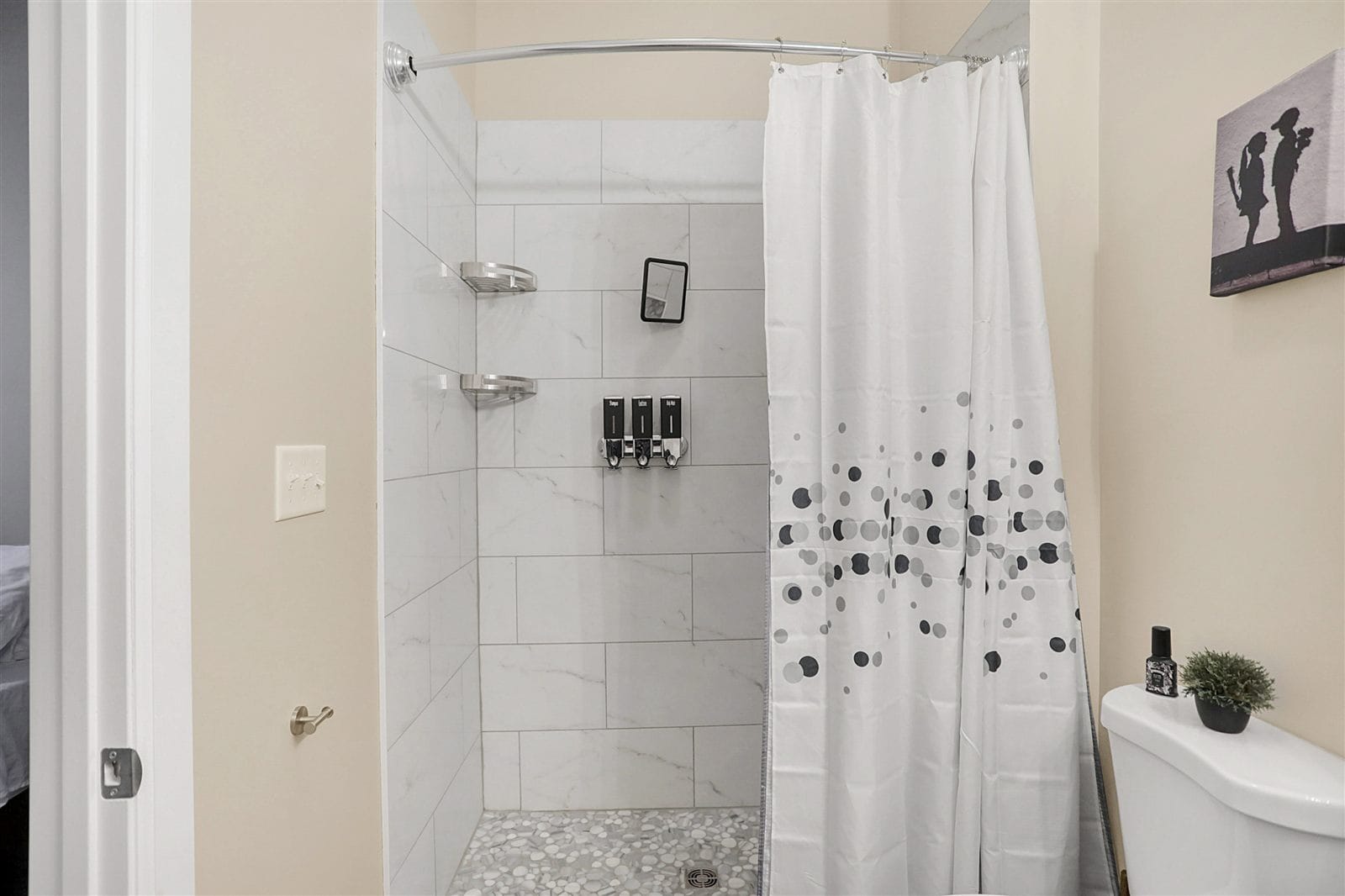 Walk-in shower with marble-look tile, niche, and pebble-tile floor